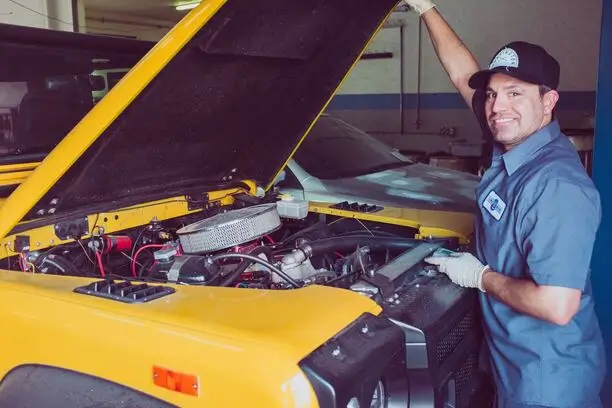 Garagiste en train changer une batterie voiture jaune.